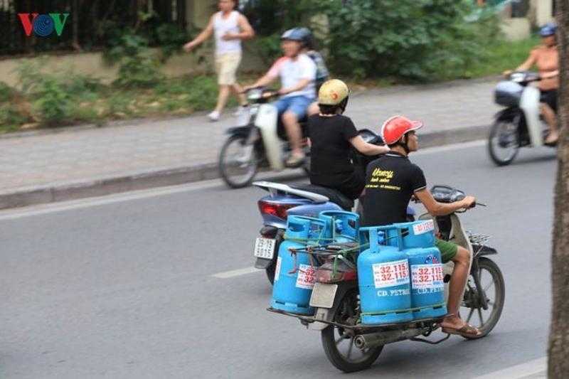 You can see someone balancing many gas tanks on a small scooter.